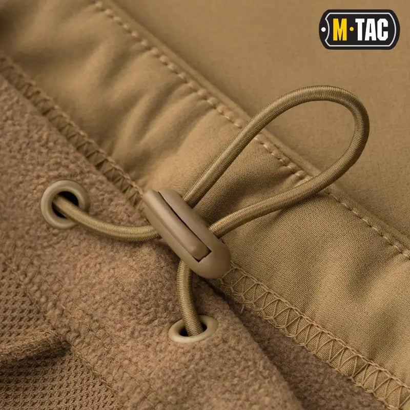 Tan drawstring cord with toggle on M-Tac Soft Shell Jacket featuring two shoulder pockets