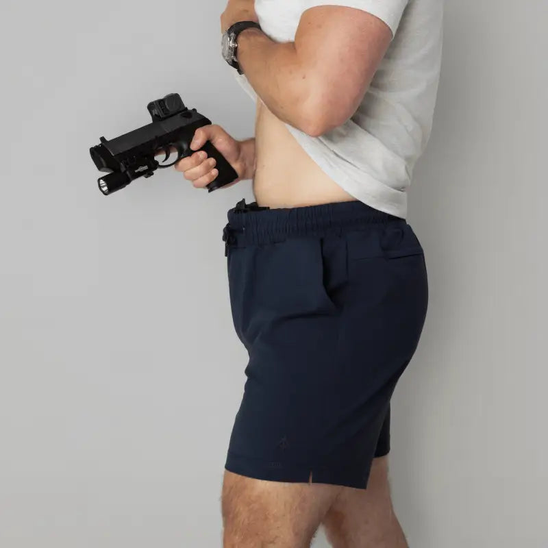 Man holding a black pistol in Arrowhead Tactical Apparel Carrier Shorts Mk.II concealed carry