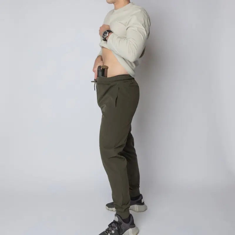 Man with gun in carrier traveler joggers showcasing concealed carry and carrier retention waistband