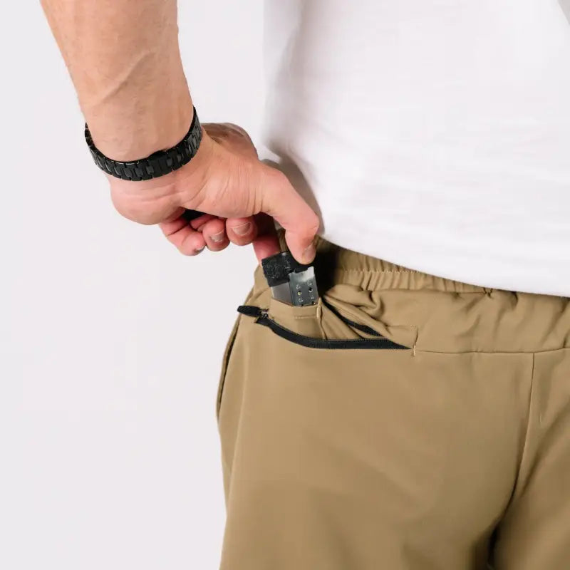 Man placing a gun in pocket wearing Carrier Shorts Mk.II for concealed carry, Arrowhead Tactical Apparel