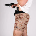 Man holding a handgun with concealed carry carrier training shorts 5 inch inseam printed