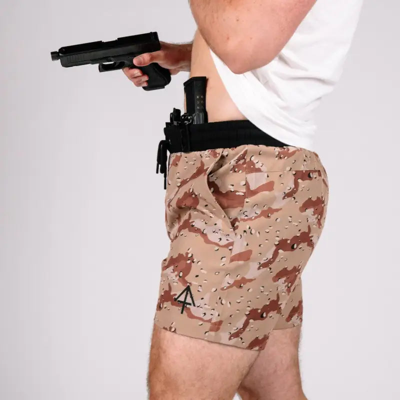 Man holding a handgun with concealed carry carrier training shorts 5 inch inseam printed