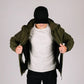 Man in olive tactical jacket Bravo with hand pocket and black cap