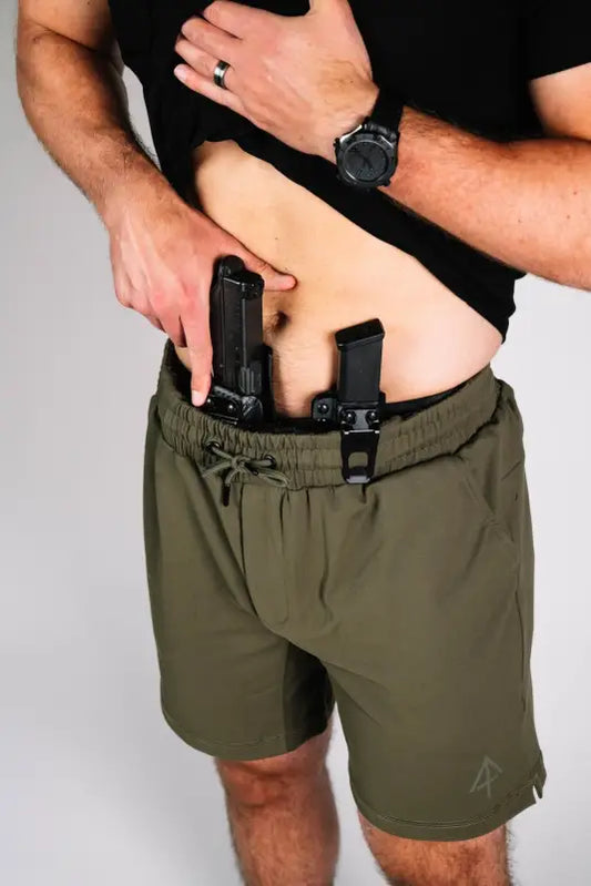 Man wearing Carrier Shorts Mk.II in Olive Drab, featuring concealed carry pockets