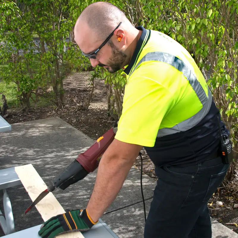 Man cutting wood with power tools wearing 32dB NRR Soft Foam Earplugs for protection