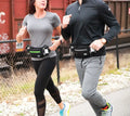 Two runners with fanny packs jogging together, featuring the Marathon Gun Pack