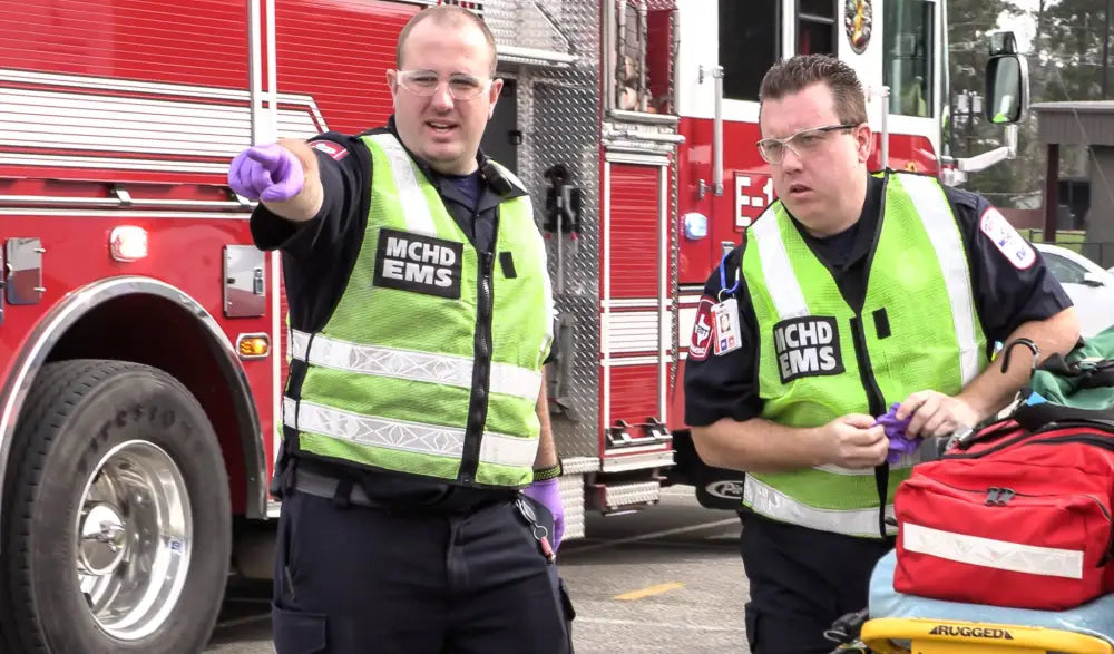 Two emergency responders in high-visibility MCHD ANSI II Adjustable Vests near fire truck