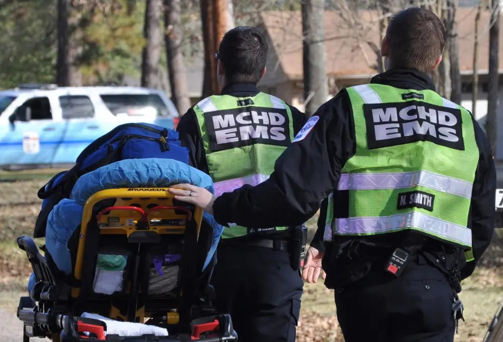 Two EMS workers in MCHD ANSI II Adjustable Vests transporting a patient on a stretcher