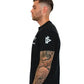 Black Men’s Gym Tee Compellence with white geometric logo and visible arm tattoo