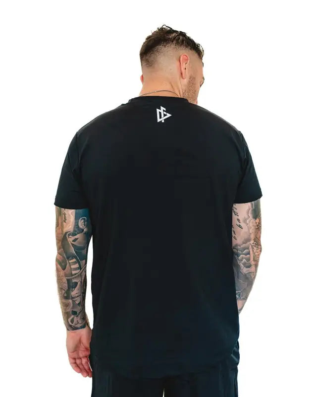 Black Men’s Gym Tee Compellence worn by a tattooed individual with an American flag design