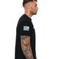 Side view of Men’s Gym Tee Compellence featuring American flag patch and arm tattoos