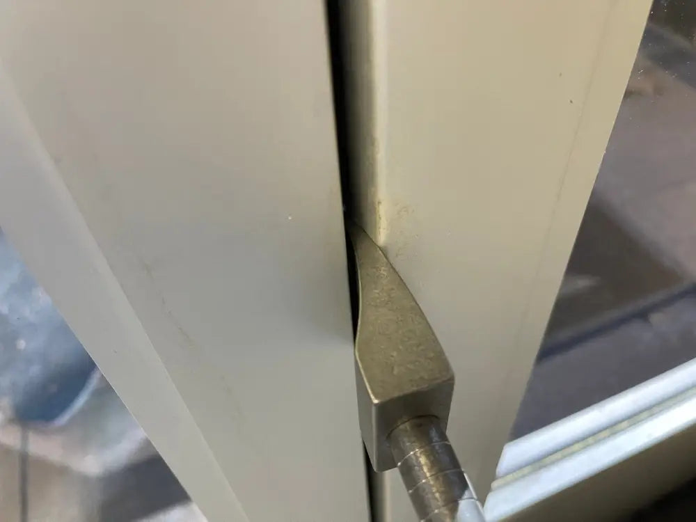 Metal door hinge mechanism on white surface, part of 12’’ XL Ti Hooligan Forced Entry Tool