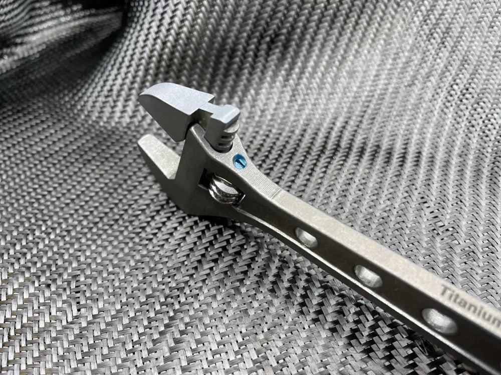 Metal nail clipper with curved cutting edge next to 8 Inch Titanium Adjustable Wrench