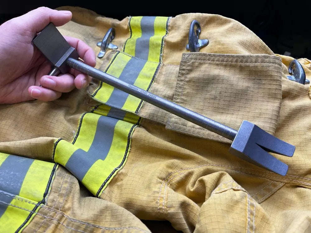 Metal tool over firefighter turnout gear showcasing the 12’’ XL Ti Hooligan Forced Entry Tool