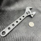 Metallic Titanium Adjustable Wrench with circular holes on handle for improved grip and versatility