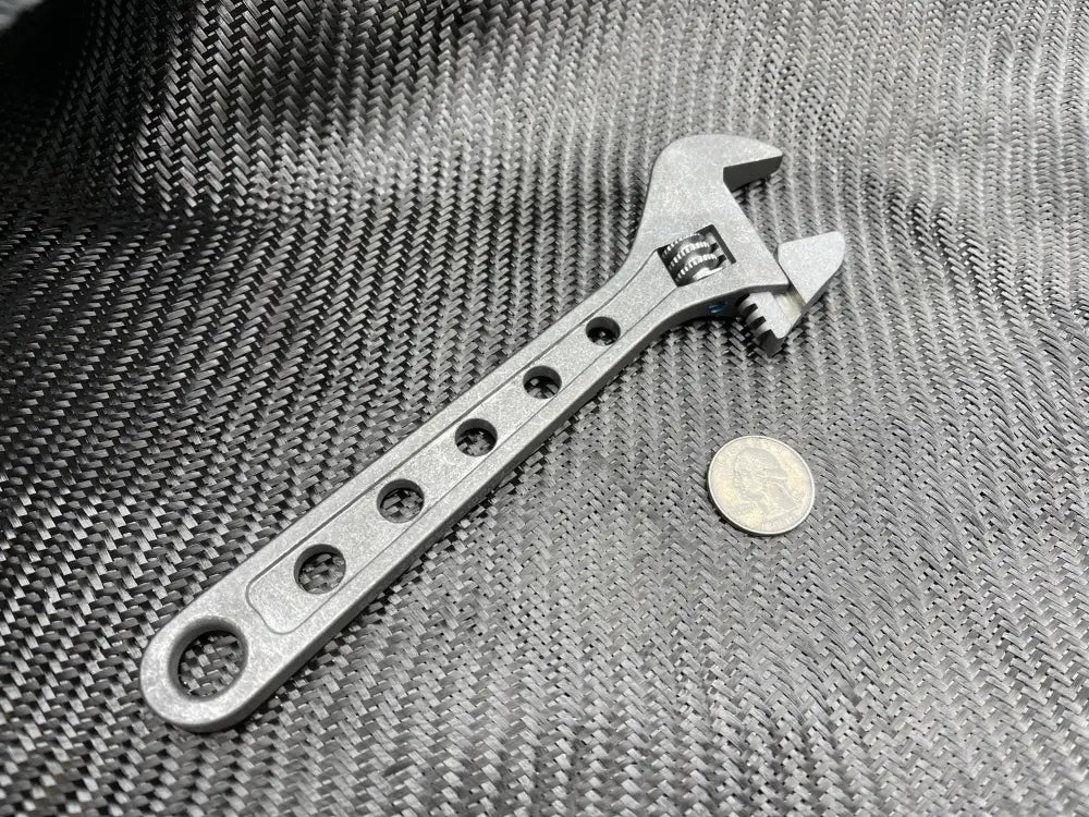 Metallic Titanium Adjustable Wrench with circular holes on handle for improved grip and versatility