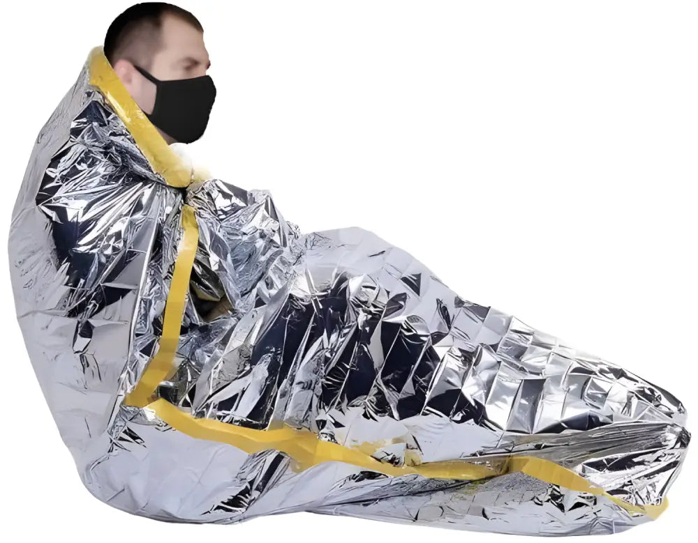 Metallic silver emergency space blanket retaining body heat around masked individual