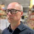 Person wearing black-rimmed glasses showcasing Metel M40 Safety Glasses with polycarbonate lenses