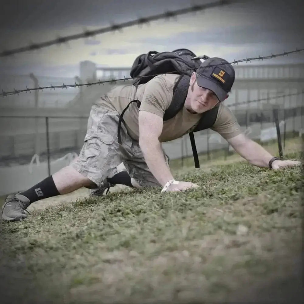 Military personnel crawling under barbed wire wearing MudGear Ruck Sock for die-hard ruckers