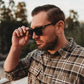 Person in sunglasses with plaid shirt, showcasing NADO frames and lens style