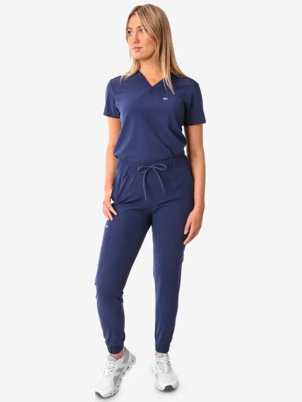 Navy blue athletic jumpsuit showcasing Women’s Tuckable One-Pocket Scrub Top design