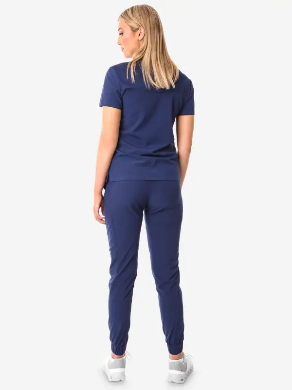 Navy blue women’s tuckable one-pocket scrub top with short sleeves and fitted pants