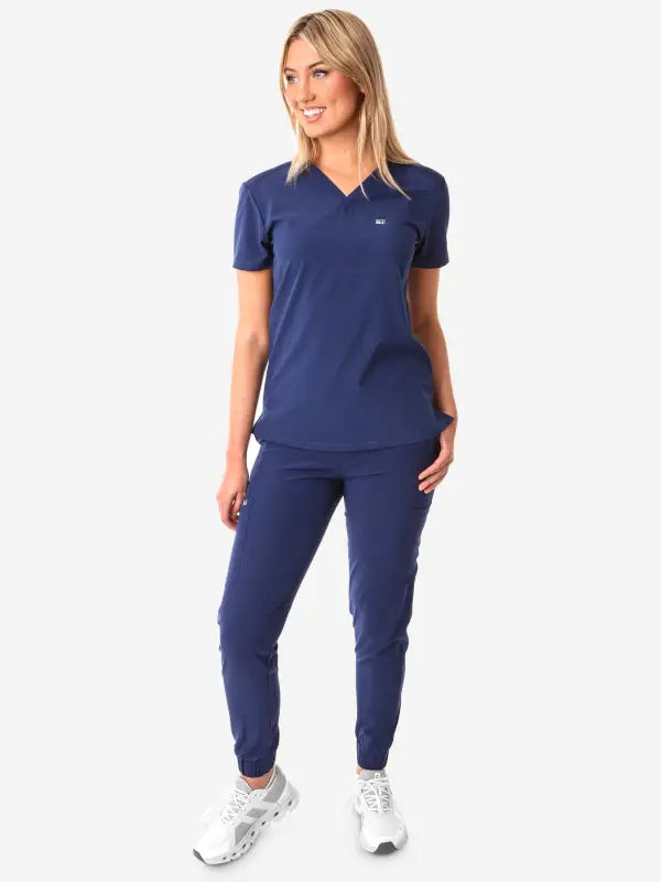 Navy blue athletic outfit featuring Women’s Tuckable One-Pocket Scrub Top and jogger pants