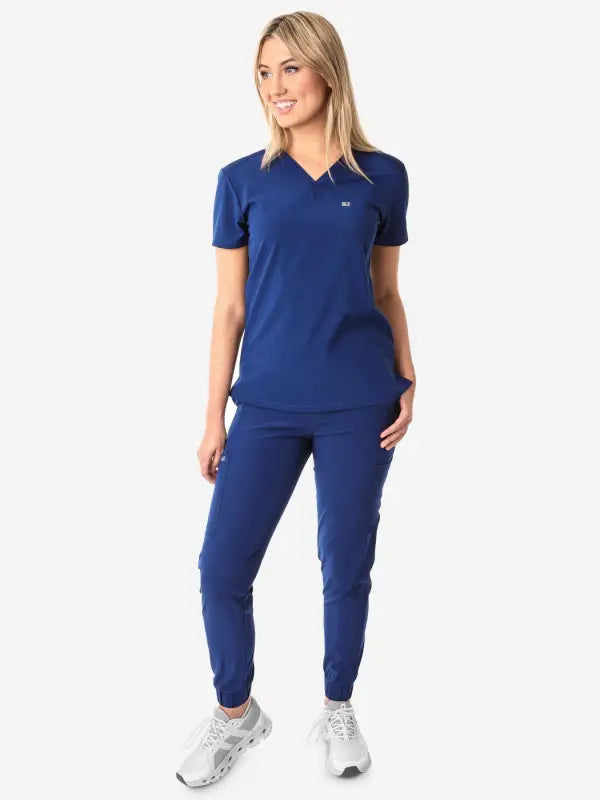 Navy blue women’s tuckable one-pocket scrub top with matching jogger pants outfit