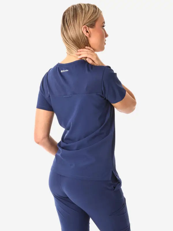 Navy blue women’s tuckable one-pocket scrub uniform shown from the back view