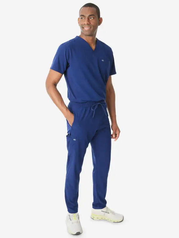 Navy blue men’s double-pocket scrub uniform with v-neck top and jogger pants