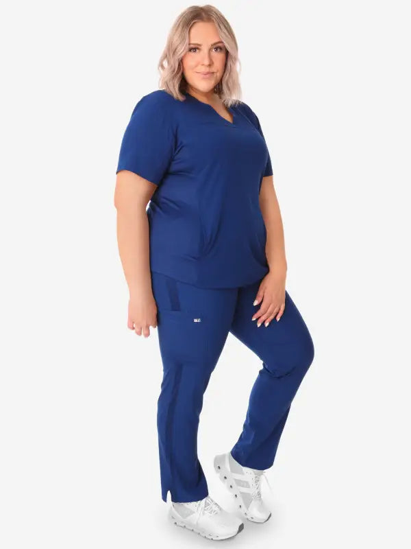 Women’s Stash-Pocket Scrub Top in navy blue paired with matching pants and white sneakers