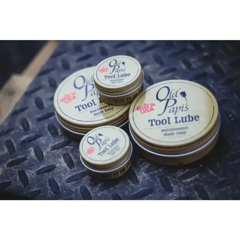 Metal tins of Old Papi’s Tool Lube with pink rose logos on the lids