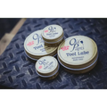 Metal tins of Old Papi’s Tool Lube with pink rose logos on the lids