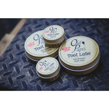 Metal tins of Old Papi’s Tool Lube with pink rose logos on the lids