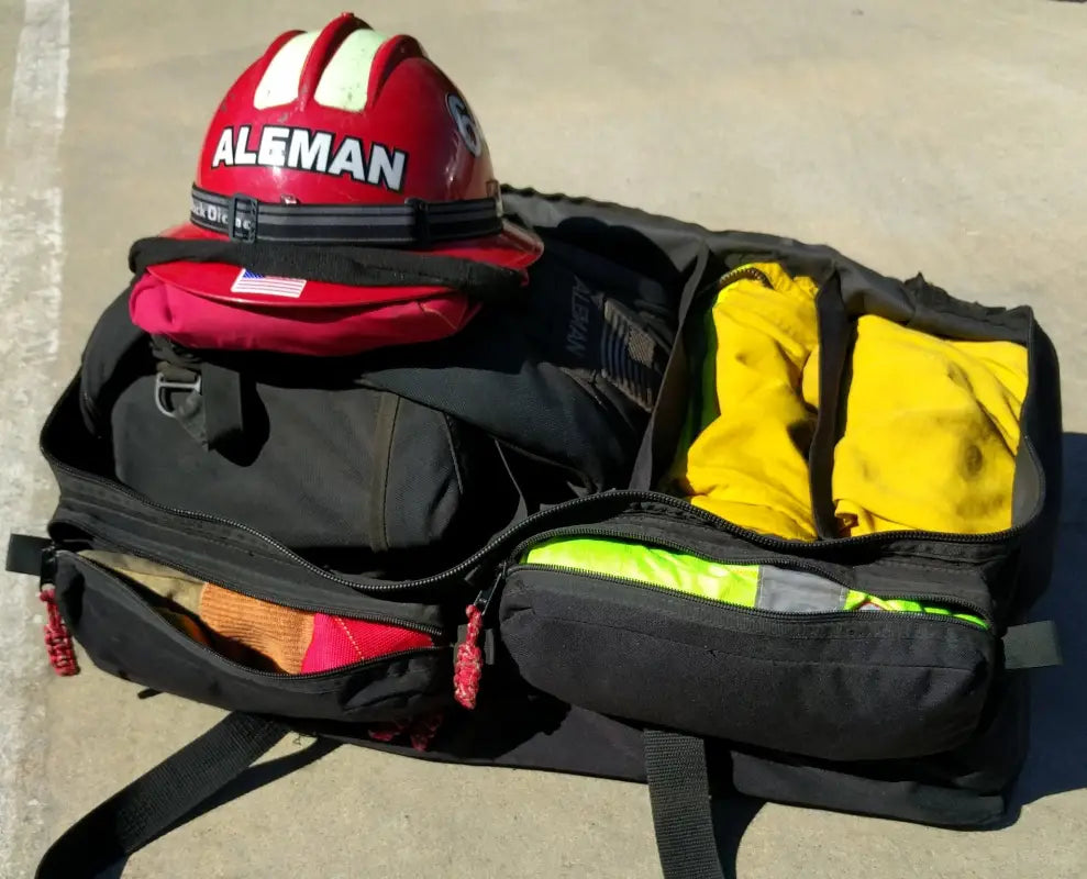 Open black duffel bag with firefighter helmet, zipper pockets, and hand grips for wildland gear