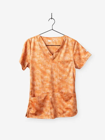 Orange patterned animal print scrub top hanging on a wire hanger for veterinary use