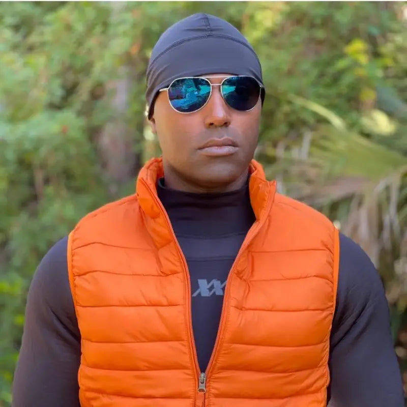 Orange puffy vest paired with a gray Equinoxx Watch Cap Beanie and blue sunglasses