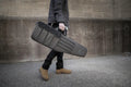 Gray padded tactical rifle case with durable construction, carried with a shoulder strap