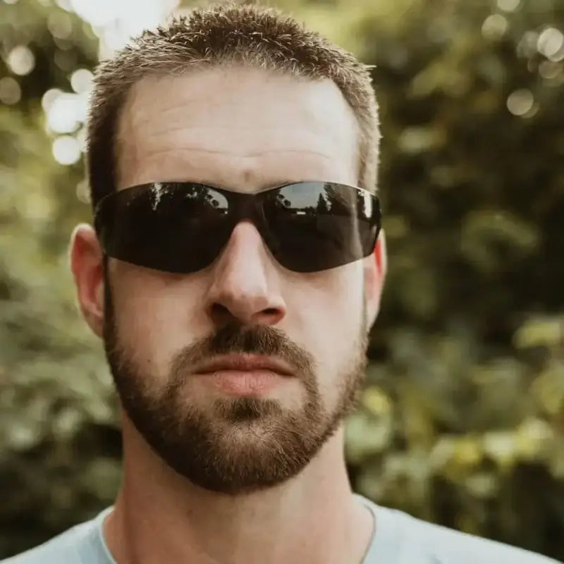 Person with dark beard and black sunglasses wearing METEL M20 Safety Glasses with wraparound lens