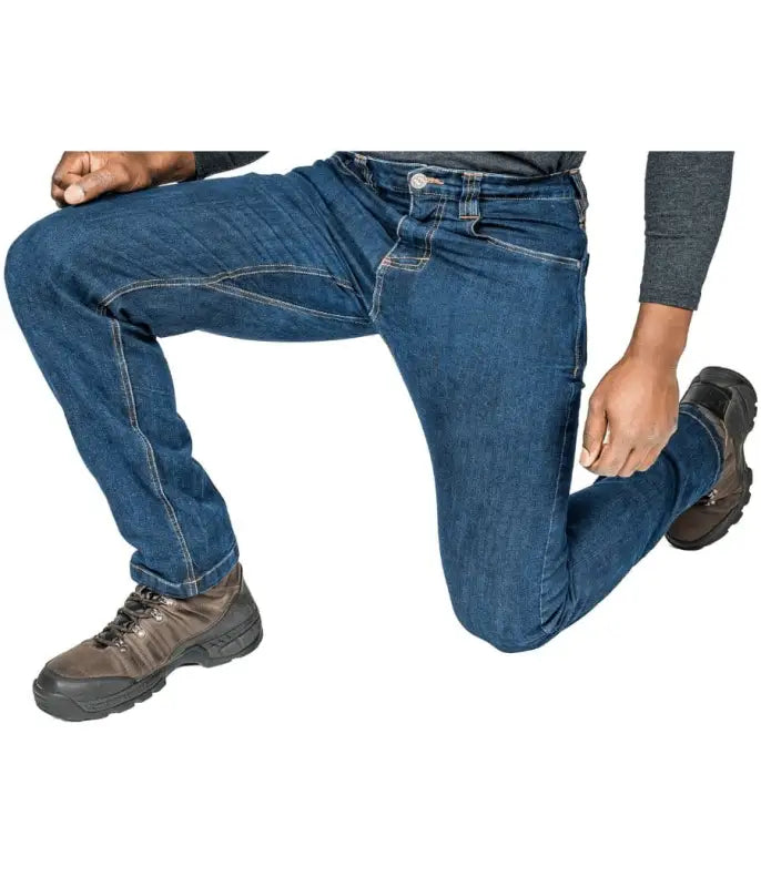 Person in Asset Tactical Jeans kneeling, showcasing blue denim and brown work boots