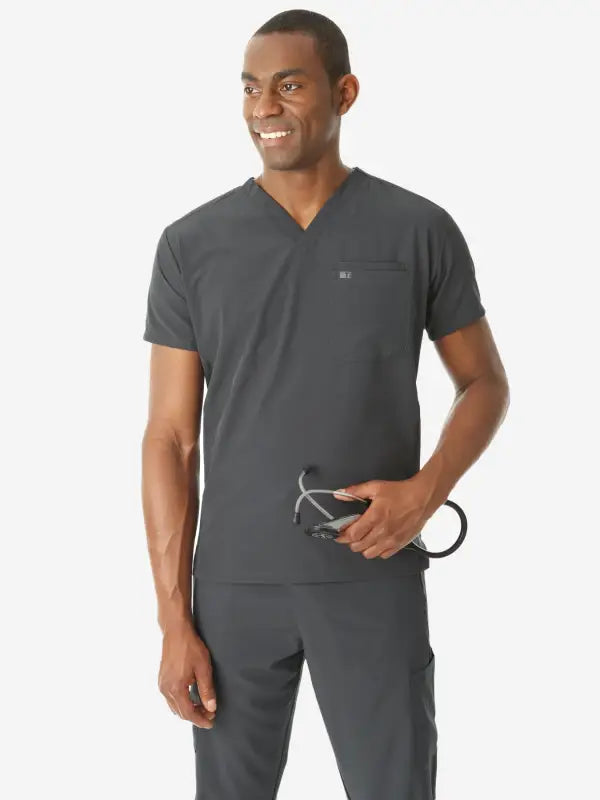 Person in gray medical scrubs showcasing men’s double-pocket scrub top design