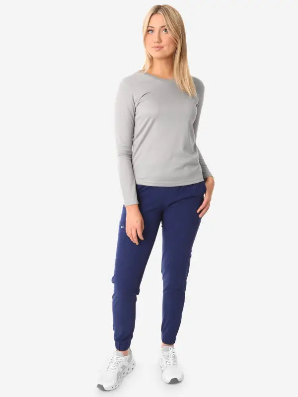 Person in grey women’s long-sleeve underscrub paired with navy joggers and white sneakers