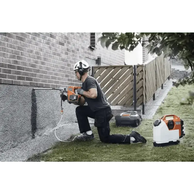 Person using Husqvarna 540i battery powered core drill kit next to a brick wall