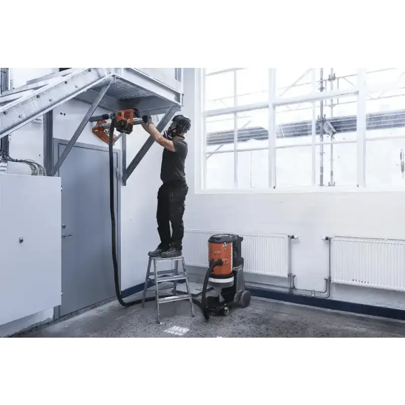 Person using Husqvarna 540i battery powered core drill kit on a step ladder for installation