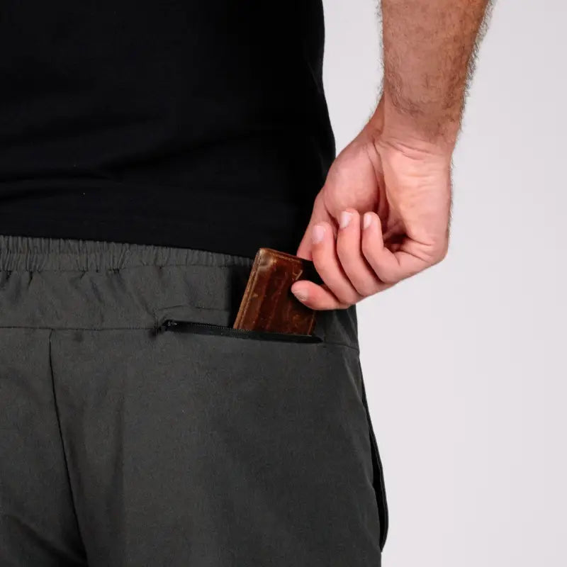 Person putting wallet in pocket of Gray Carrier Traveler Joggers with concealed carry carrier retention waistband
