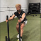 Person pushing a weighted sled on turf using AEROSx Lung Trainer for better performance