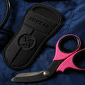 Pink and black trauma shears with black titanium coated blades and protective sheath