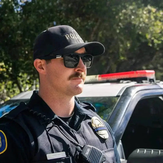 Police officer in tactical gear with frontline optics beside patrol vehicle Pomona