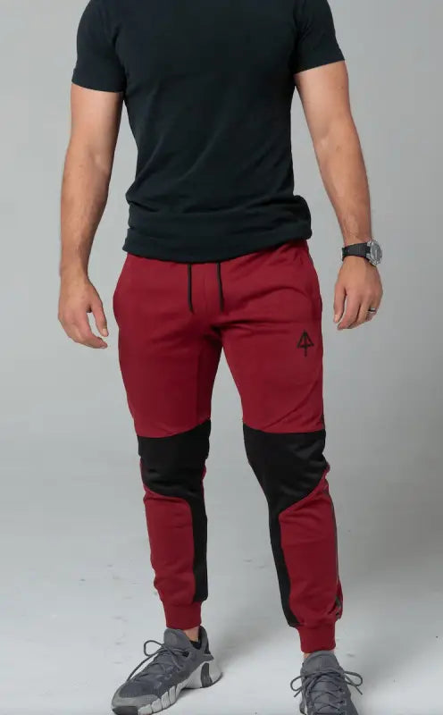 Red athletic jogger pants with black knee patches and elastic cuffs for concealed carry