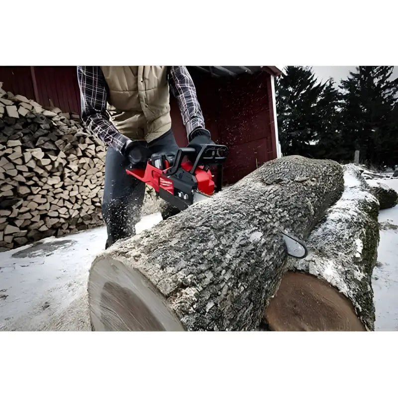 Red Milwaukee 2727-20C M18 FUEL™ 14’’ Chainsaw cutting through a snow-dusted log